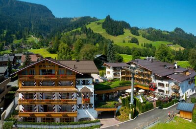 Mehrstöckiges Hotelgebäude in alpiner Bauweise mit Holzfassade und Seilbahnstation im Vordergrund.