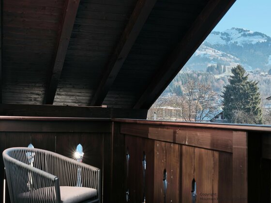 Balkon im Obergeschoss Holzbalkon mit modernem Sessel und Blick auf schneebedeckte Berge.