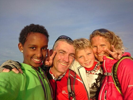 Vierköpfige Familie in Sportkleidung macht ein Selfie im Freien.