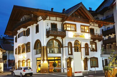 Bäckerei Schmidt in der Abenddämmerung Beleuchtetes Gebäude der Bäckerei Schmidt bei Dämmerung mit weißer Fassade und Holzbalkonen.