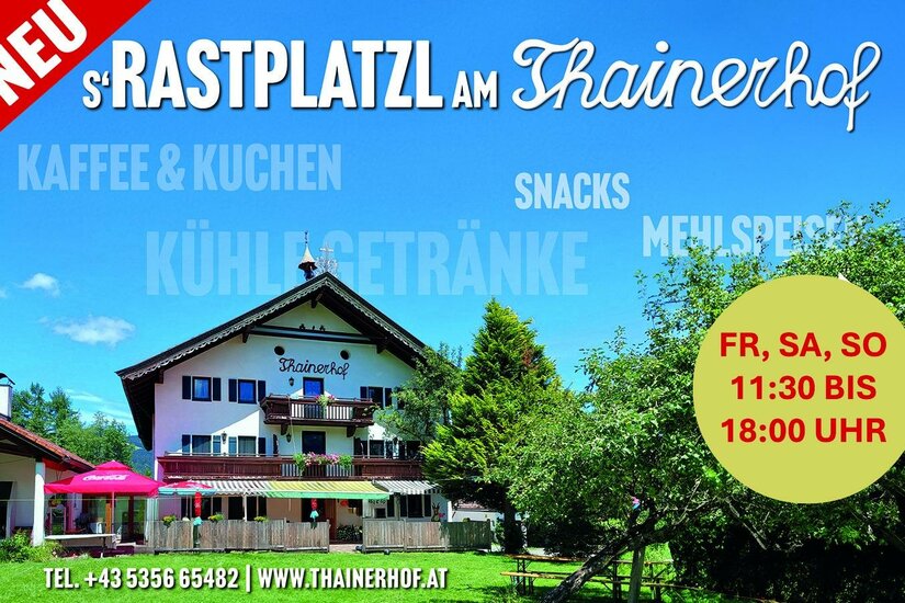Thainerhof Rastplatzl Außenansicht des Thainerhofs mit Terrasse, Sonnenschirmen und umliegenden Bäumen unter blauem Himmel.