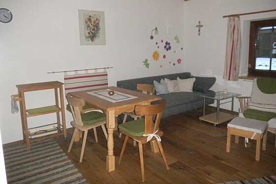 Wohnbereich mit Holztisch, Stühlen, grauem Sofa und Holzboden in einer Unterkunft.