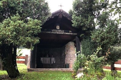 Veitlkapelle Eine kleine Kapelle, umgeben von grünen Bäumen und Pflanzen. Der Eingang ist mit einem Gitter versehen und ein Kreuz befindet sich auf dem Dach.