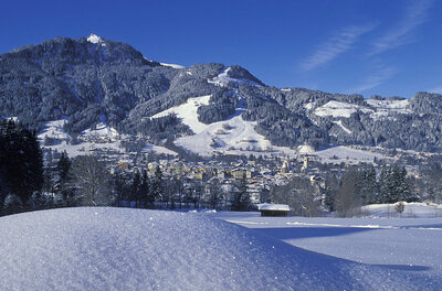 Verschneite Berglandschaft mit Blick auf Kitzbühel unter blauem Himmel.