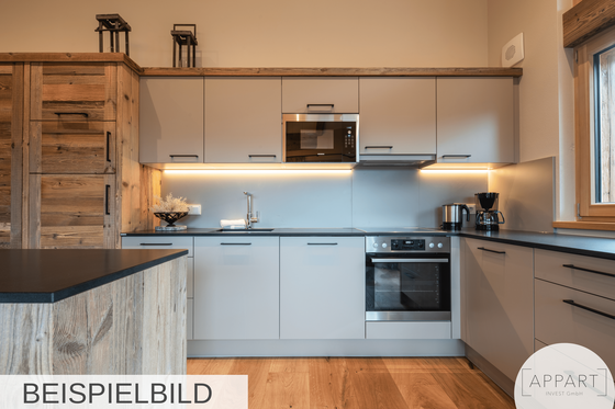 Moderne Küchenzeile mit hellgrauen Fronten, Holzschränken und integrierten Elektrogeräten.