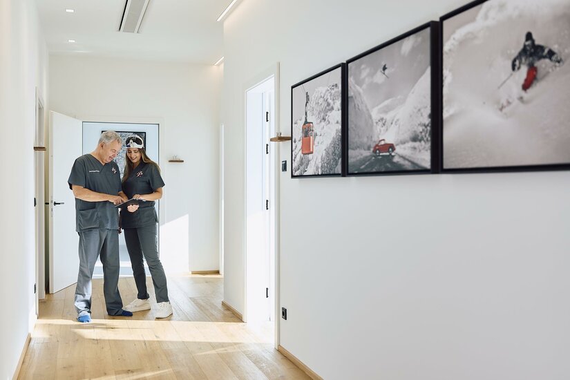 Ein heller Flur mit modernem Design. Zwei Personen stehen nebeneinander und betrachten Bilder an der Wand.