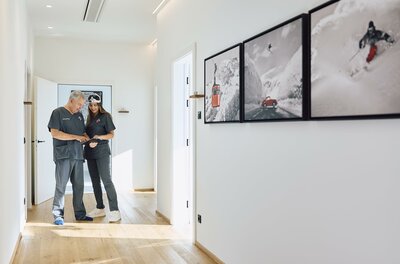 Ein heller Flur mit modernem Design. Zwei Personen stehen nebeneinander und betrachten Bilder an der Wand.