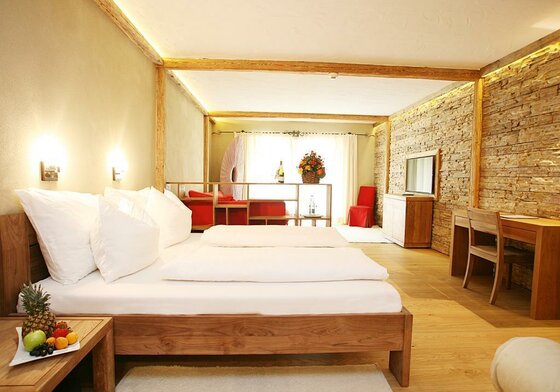 Modernes Hotelzimmer mit Doppelbett aus Holz, Steinwand und Schreibtisch.
