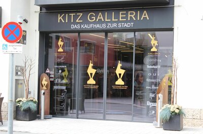 Eingangsbereich der Kitz Galleria mit Glastüren und goldenen Logos.