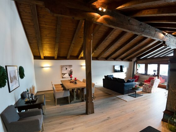 Großzügiger Wohn- und Essbereich mit Holzbalkendecke, Esstisch und Sofaecke.
