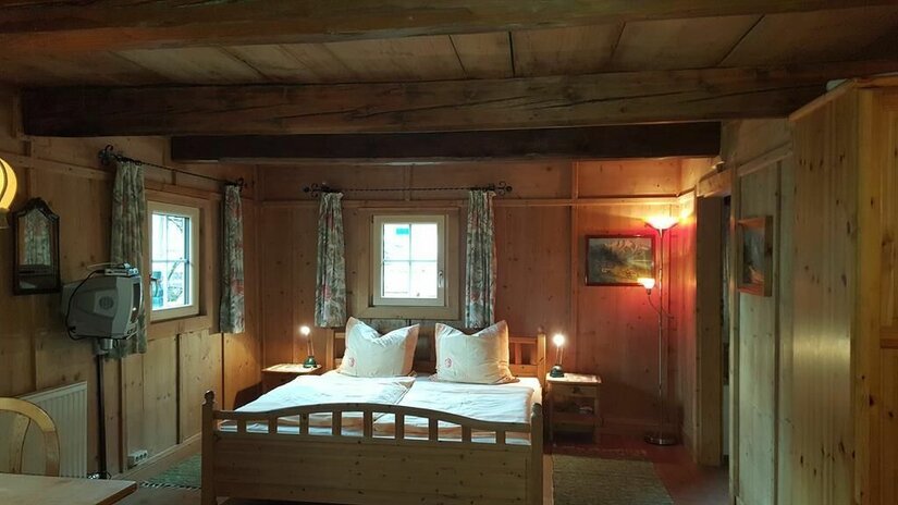 Schlafzimmer im Angererhof Rustikales Schlafzimmer mit Holzwänden, Doppelbett und Deckenbalken im Angererhof.
