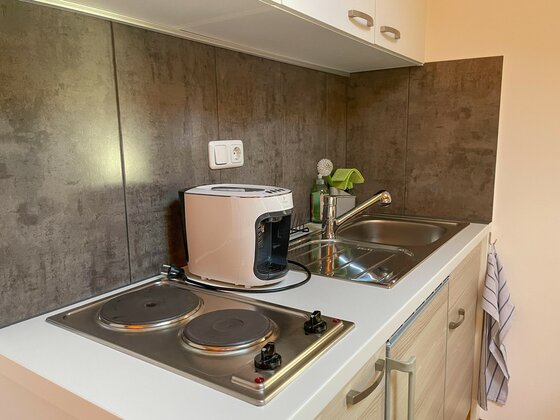 Küchenzeile der Ferienwohnung Kleine Küchenzeile mit Zwei-Platten-Herd, Kaffeemaschine und Spülbecken.