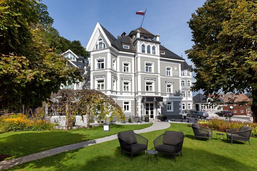 Mehrstöckiges graues Boutiquehotel mit weißer Fassadengliederung und Gartenanlage.