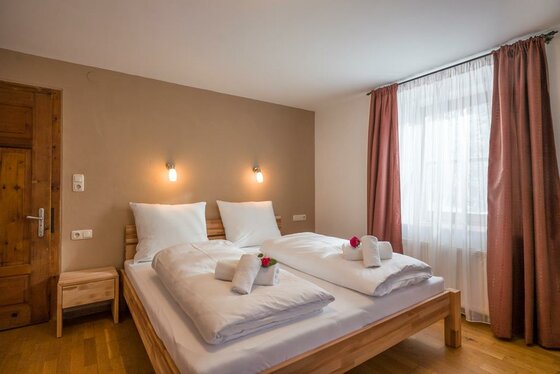 Schlafzimmer im Haus Wetti Doppelbett aus Holz mit weißer Bettwäsche in einem hellen Schlafzimmer.