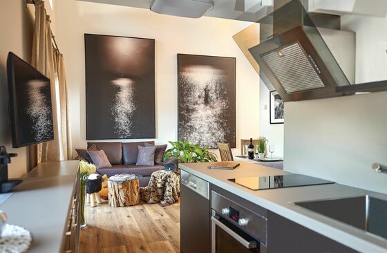 Küche und Wohnbereich Moderner Wohn- und Kochbereich mit dunklem Sofa, Holztisch und Küchenzeile.