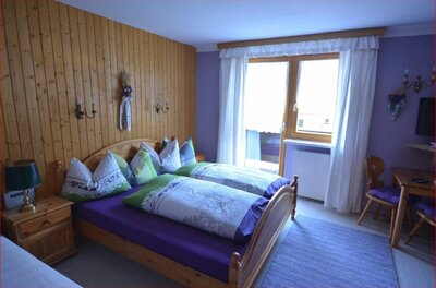 Doppelbett aus Holz in einem Zimmer mit Holzvertäfelung und lila Wänden.