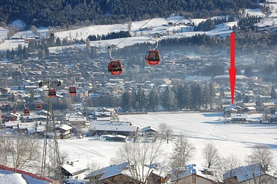 Zentral gelegenes Hotel Edelweiss Blick auf eine Seilbahn mit roten Gondeln über einem verschneiten Dorf im Tal.