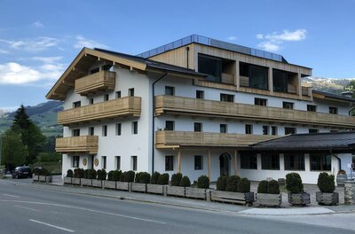 Mehrstöckiges Hotelgebäude mit weißen Wänden und Holzbalkonen an einer Straße.
