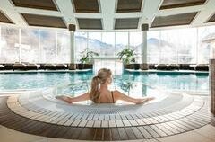 Grand Alp Spa - Grand Tirolia Kitzbühel <p>Der Spa Bereich vom Grand Tirolia Kitzbühel mit einem großen Pool und Blick auf die Kitzbüheler Berge. Eine Frau sitzt am Rand des Pools und genießt die ruhige Atmosphäre.</p>