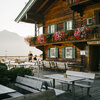 Terrasse beim Gasthaus Haggstein mit Holztischen, umgeben von Pflanzen und Bergen.