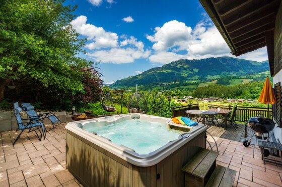Außenbereich mit Whirlpool, Liegestühlen und Bergblick.