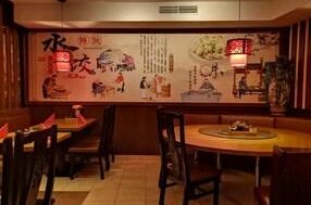 Shang Hai China Restaurant Innenansicht eines China-Restaurants mit runden Holztischen und einer großen Wandmalerei mit asiatischen Motiven.
