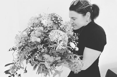 Schwarz-Weiß-Aufnahme einer Frau, die an einem großen Blumenstrauß riecht.