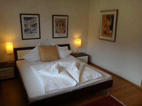 Doppelbett mit weißer Bettwäsche, zwei Nachttischen und Bildern an der Wand.