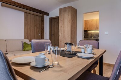 Gedeckter Holztisch mit Geschirr und Gläsern in einem modern eingerichteten Apartment.