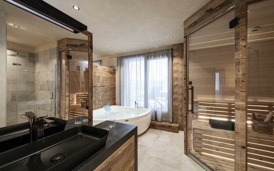 Moderner Wellnessbereich mit Sauna, Whirlpool und schwarzem Waschbecken in Holzoptik.