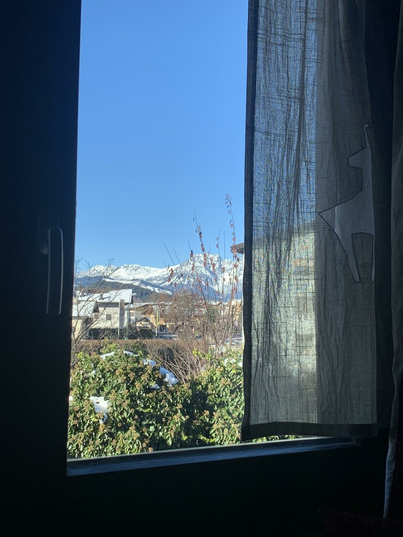 Bergblick aus der Ferienwohnung Blick aus einem Fenster auf schneebedeckte Berggipfel unter blauem Himmel.