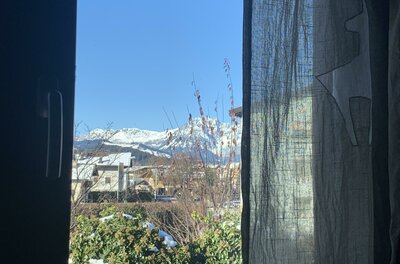 Bergblick aus der Ferienwohnung Blick aus einem Fenster auf schneebedeckte Berggipfel unter blauem Himmel.