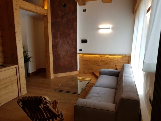 Moderner Wohnbereich mit grauem Sofa, Glastisch und Holzelementen.