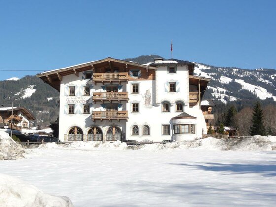 Hotel Wiesenegg im Winter Mehrstöckiges Hotelgebäude im alpinen Stil vor verschneiten Bergen unter blauem Himmel.