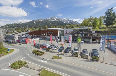 Sportpark Kitzbühel Außenansicht des Sportparks Kitzbühel mit Parkplatz, Gebäuden und Bergen im Hintergrund.