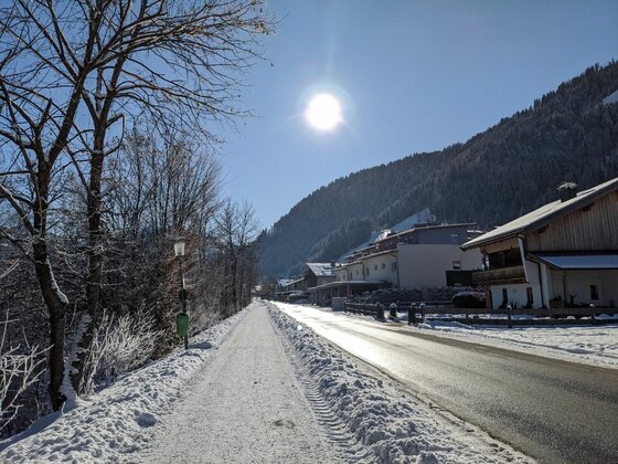 Winterlicher Weg in Malerndörfl Verschneiter Gehweg neben einer Straße in Malerndörfl bei Sonnenschein.