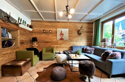 Rustikaler Loungebereich mit Holzverkleidung, Sofas, Sesseln und Jagddekor.