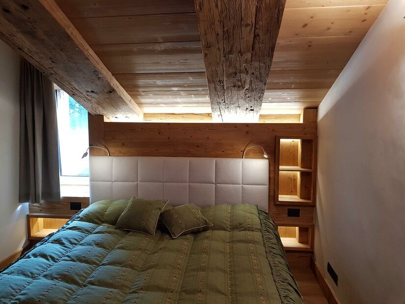 Doppelbett in einem Zimmer mit Holzdecke und Holzwänden.