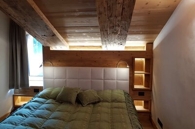 Schlafzimmer Apartment Südberge Doppelbett in einem Zimmer mit Holzdecke und Holzwänden.