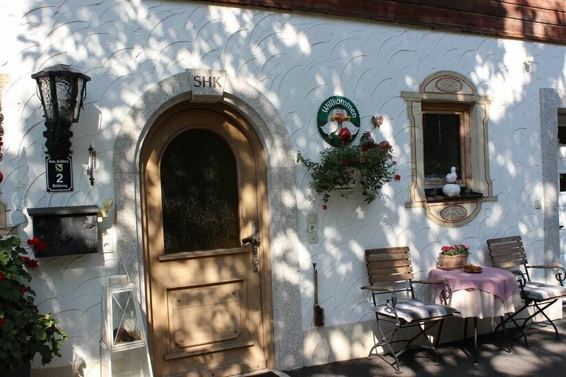 Eingang Haus Kreidl Hauseingang mit Rundbogentür aus Holz, Steinfassung und einer kleinen Sitzgruppe davor.