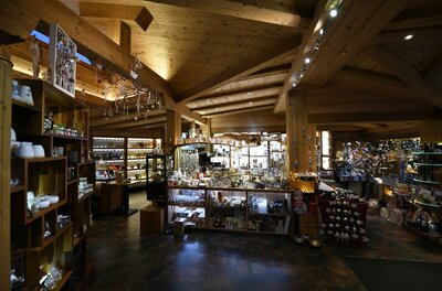 Innenansicht eines Ladengeschäfts mit Holzdecke, Regalen voller Kunsthandwerk und dekorativer Beleuchtung.