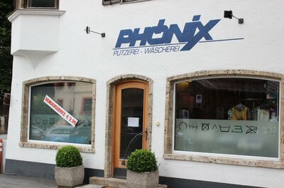 Phönix Ein Geschäft mit dem Namen "Phoenix" für Reinigung und Wäscherei. Die Fassade ist hell und modern mit großen Fenstern.