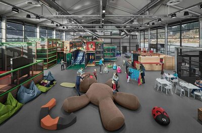Großer Indoor-Spielplatz mit Klettergerüsten, Rutschen und Sitzsäcken in einer modernen Halle.