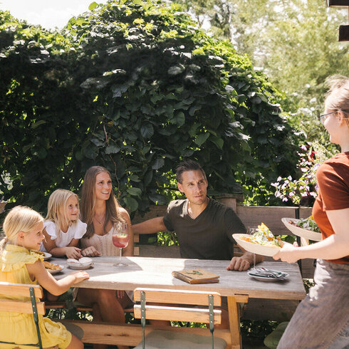 Familie sitzt bei herrlichem Wetter in einem Restaurant in Kitzbühel