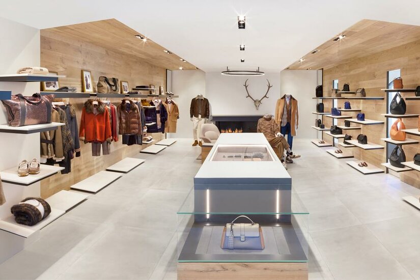 Brunello Cucinelli Ein moderner Modegeschäft mit stilvollen Kleidungsstücken und Accessoires. Die Wände sind aus Holz und die Präsentation ist minimalistisch.