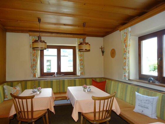 Frühstücksraum Gästehaus Wallner Rustikaler Frühstücksraum mit Holzhintergrund, Eckbank und zwei eingedeckten Tischen.