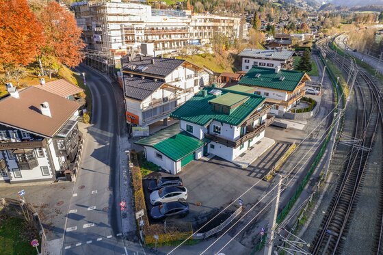 Luftaufnahme von Wohnhäusern neben einer Bahnstrecke und einer Straße in Kitzbühel.