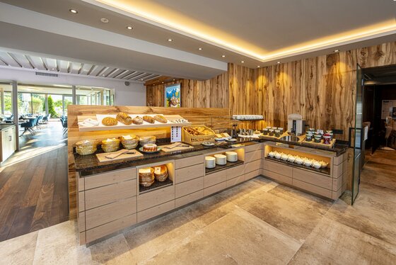 Ein einladendes Frühstücksbuffet mit frischen Lebensmitteln und Getränken. Der Raum hat eine moderne und gemütliche Atmosphäre.