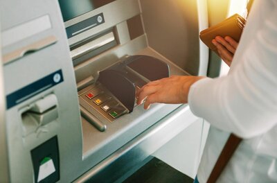Nahaufnahme einer Person, die eine PIN an einem Bankautomaten eingibt.