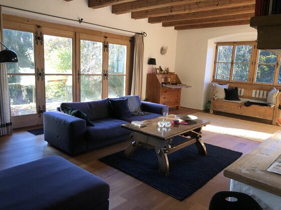Wohnbereich im Lutzenberg 19 Wohnzimmer mit blauem Sofa, Holztisch und rustikaler Balkendecke.